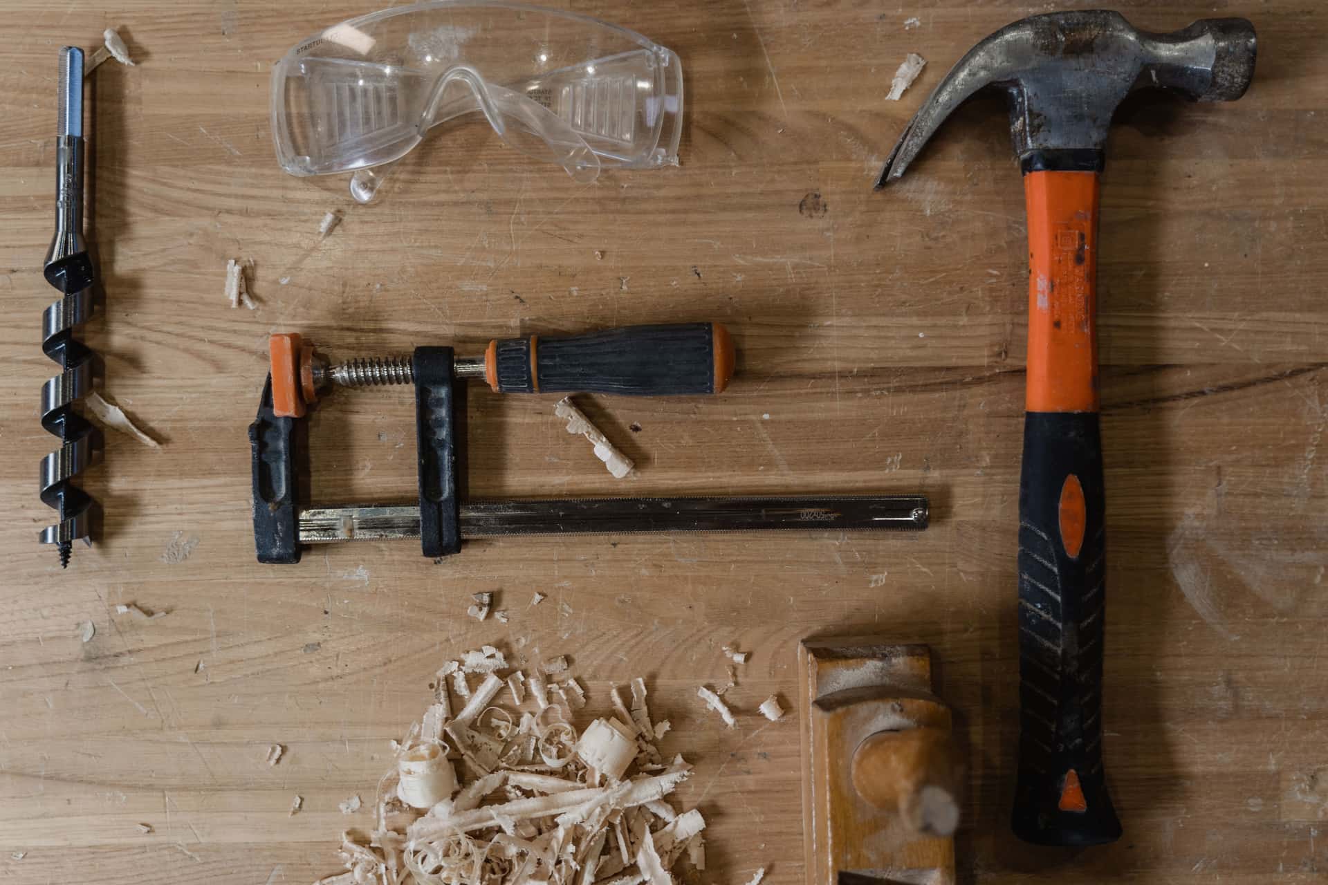 A set of essential beginner woodworking hand tools arranged on a workbench